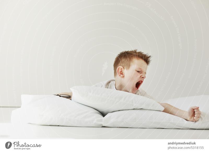 child boy wakes up and stretching on his comfortable bed in morning, Health care and good morning world concept. Stretches and yawns. lifestyle person pillow