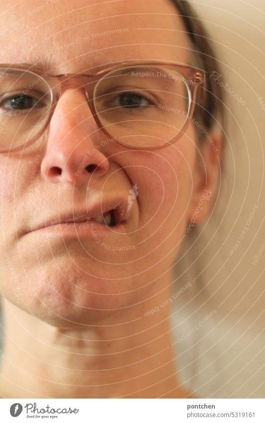 a woman pulls up one corner of her mouth. annoyed facial expression Corner of the mouth sensation emotion Exasperated Woman Face portrait Eyeglasses Mouth