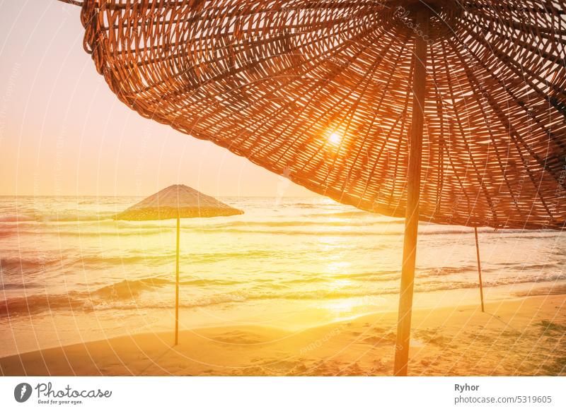 Wicker Beach Umbrella At Mediterranean Resort. Vacation Concept. Advertising Travel Company. Beach Umbrella On Idyllic Tropical Sand Beach. Concept For Rest, Relaxation, Holidays, Spa, Resort Design
