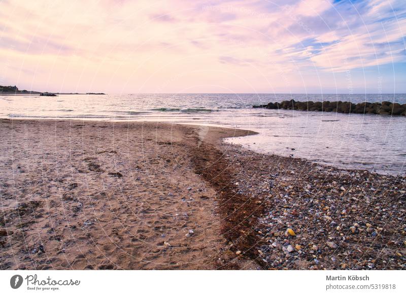 Stone beach on the Darss at sunset. Baltic Sea with light waves and pastel colors on the sky. Landscape photo from the coast sand vacation light mood travel