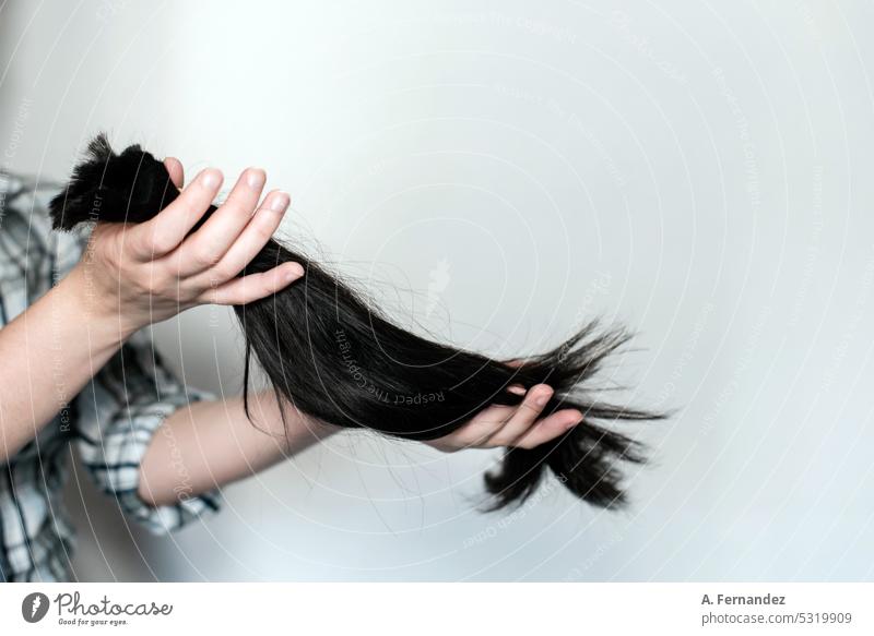 Young woman holding a section of hair in a ponytail that she has just cut. Concept of hair donation for cancer patients haircut hair cut makeover donate
