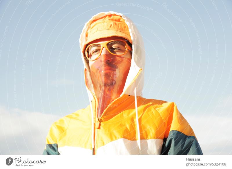 photo concept about a person wearing a sport outfit and orange hat with transparent mask and funky glasses without glass lifestyle garment colorful cloth