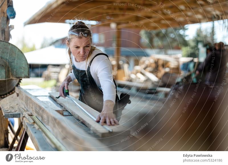 Woman working with wooden planks in a sawmill real people woodshop carpenter entrepreneur expertise craftsperson creativity manufacturing crafts people hobby