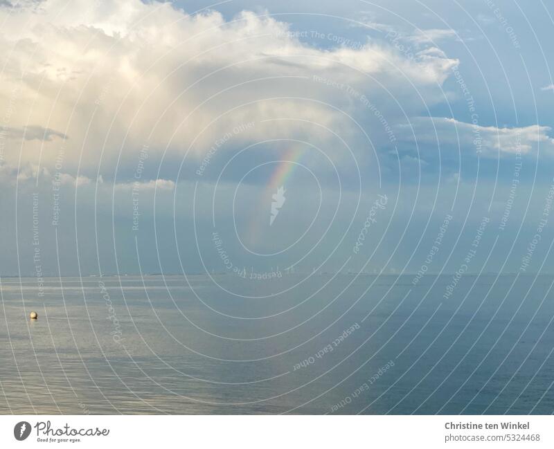 A rainbow and pretty clouds over the calm North Sea, in the background wind turbines on the mainland Rainbow tranquillity soft light Reflection Sky Water Calm