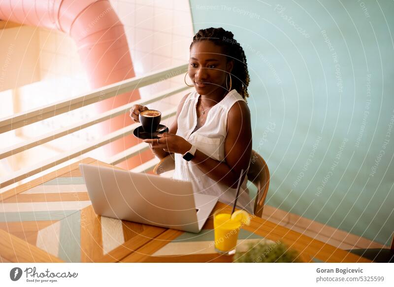 Young black woman drinking coffee  while working on laptop in the cafe african african american afro afro hairstyle attractive charming communication computer