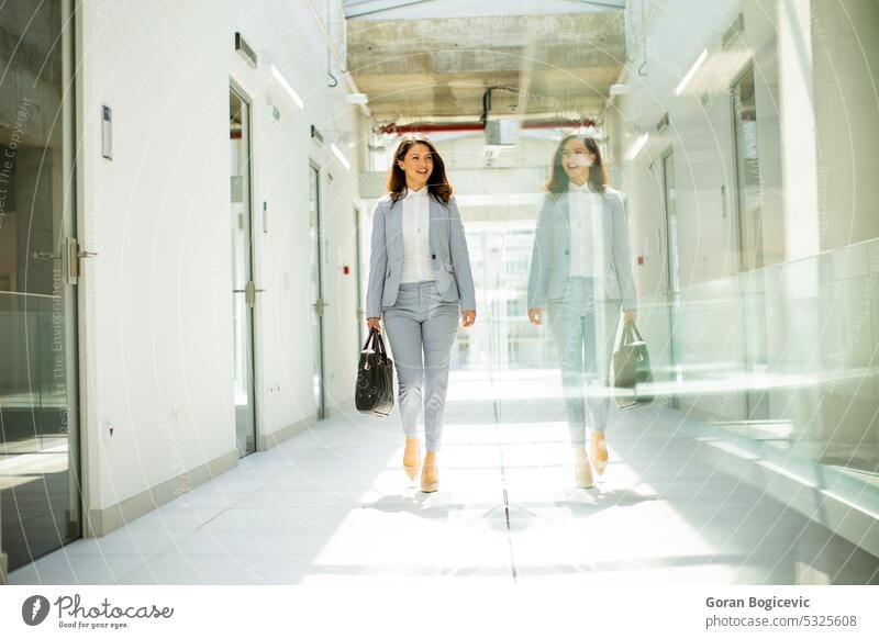 Pretty young business woman walking with briefcase in the office hallway caucasian adult achievement attractive bag beautiful business lifestyle businesswoman