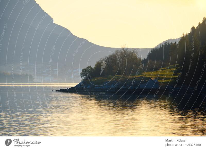 Sunset on the fjord with mountains in Norway. Diffuse light, sun rays on a meadow Fjord sunset recreation nature wilderness panorama romantic nordic water fresh