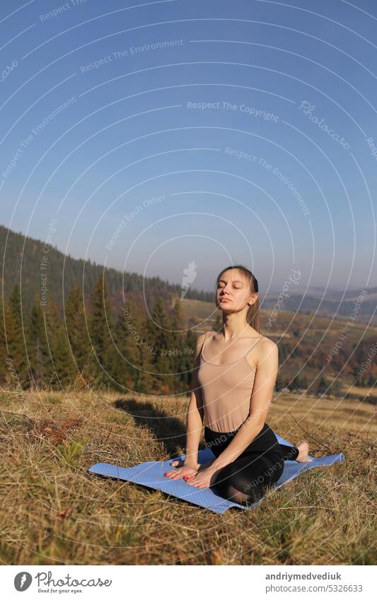 Young girl doing yoga fitness exercise outdoor in beautiful mountains landscape. girl doing morning exercise on a meadow in the mountains. Meditation and Relax. Healthy Lifestyle.
