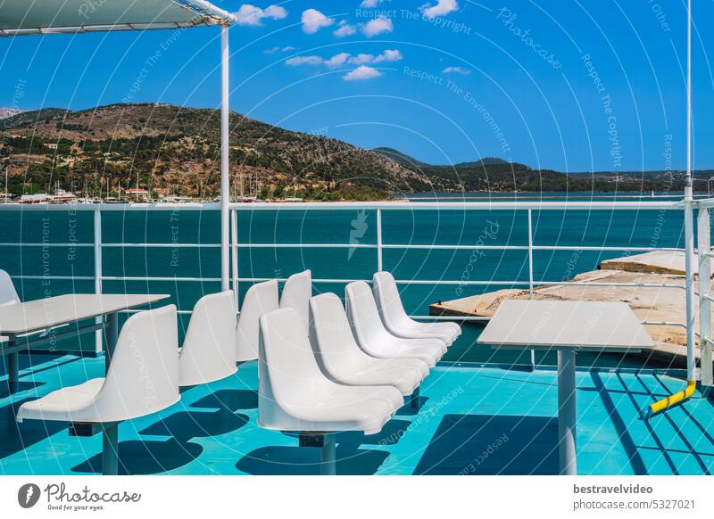White empty plastic fiberglass chairs and seating area with tables on a ferry boat under a bright summer sky. Transportation ferry boat chairs deck seating view