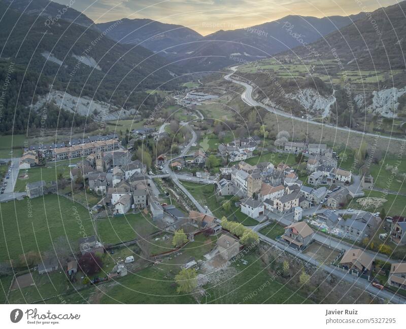 aerial image of a quiet village in a valley between mountains at sunset, with a road disappearing in the horizon, Fiscal, Huesca, Spain pyrenees drone view