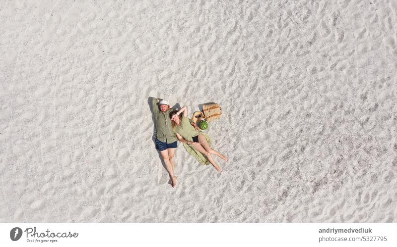 Aerial view of a young couple lying on the white sand. man and woman spend time together and travel through the desert aerial beach vacation turquoise nature