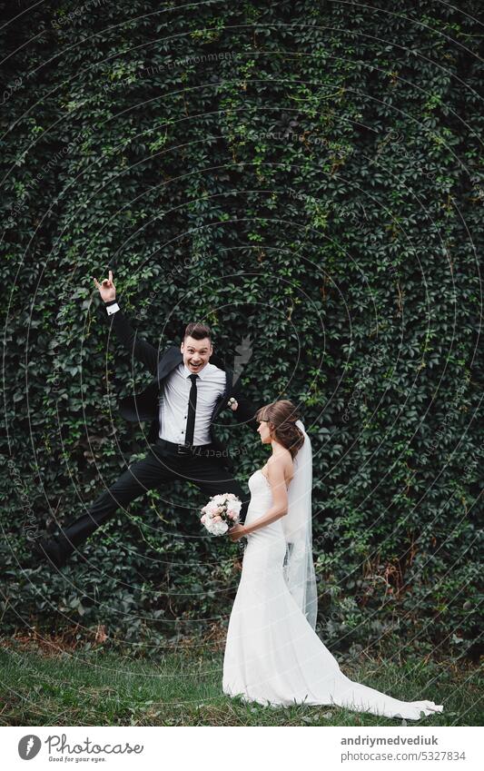 happy gorgeous bride and stylish groom jumping and having fun, wedding couple, luxury wedding. fun and crazy brides together background beautiful dress family