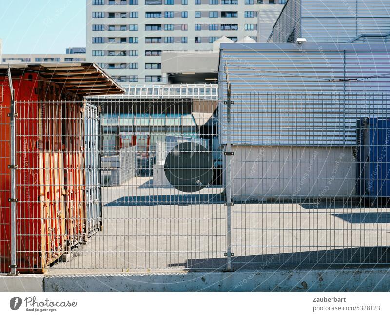 Construction fence blocks off a commercial courtyard, behind it light gray concrete facades and residential building Hoarding Facade Commerce industrial yard