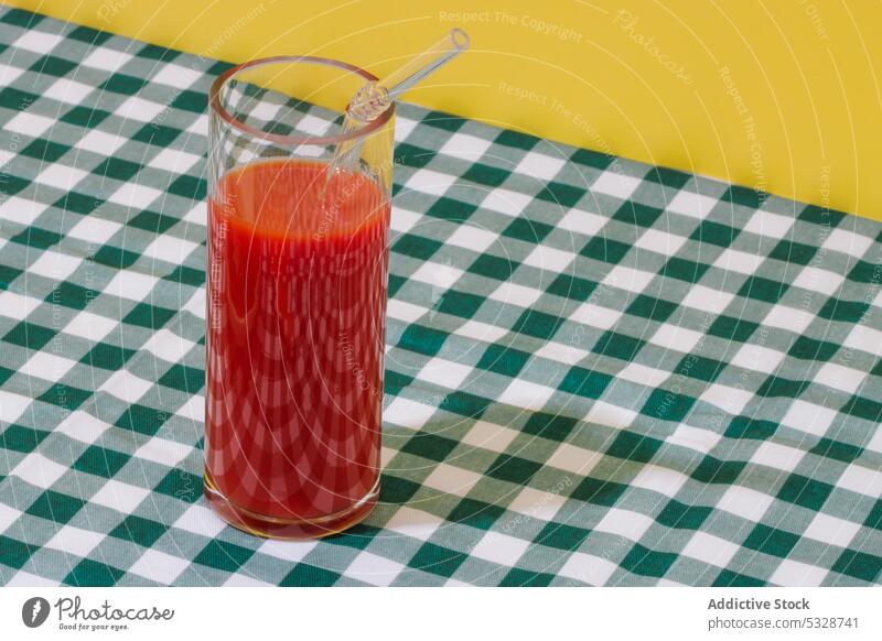 Glass of refreshing tomato juice with straw checkered glass eco friendly zero waste tablecloth bright ripe cocktail natural reuse colorful drink beverage