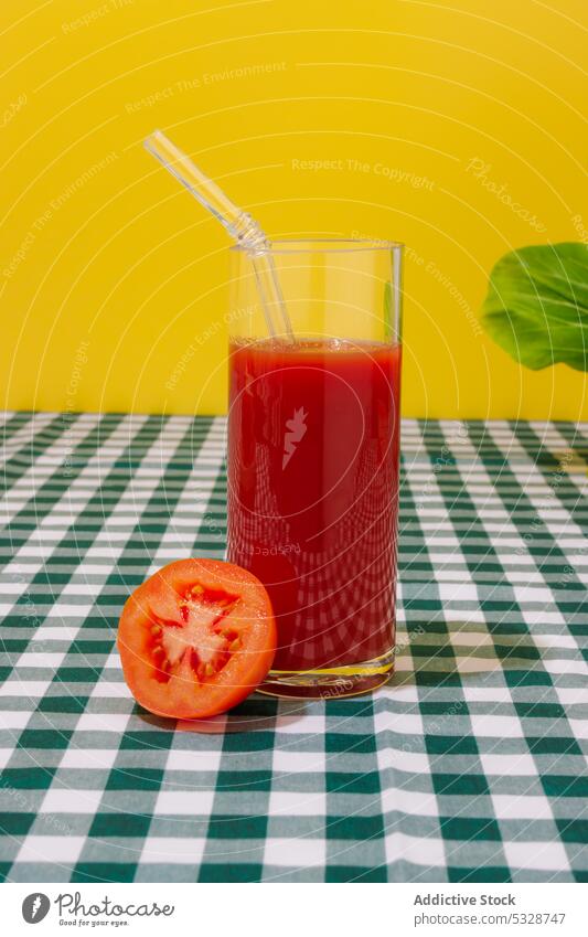 Glass of refreshing tomato juice with straw checkered glass eco friendly zero waste tablecloth bright ripe half cocktail natural reuse colorful drink beverage