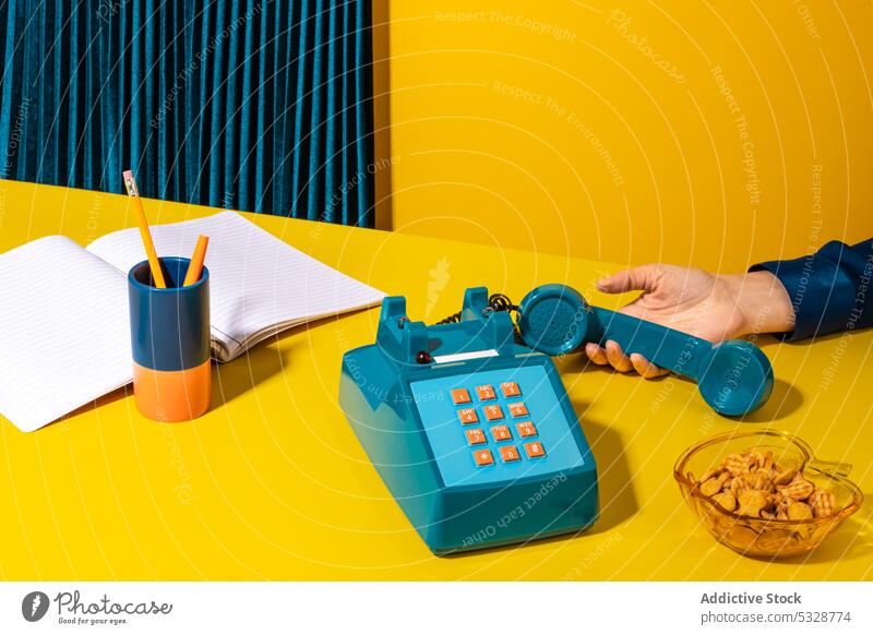 Person picking up phone placed near office supplies person pick up hang up handset retro stationary telephone notebook planner cookie supply old fashioned