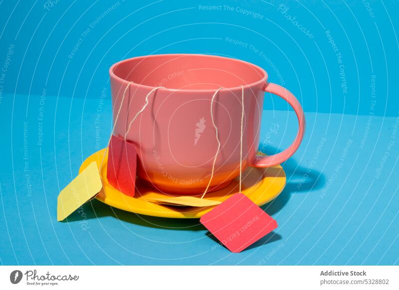 Pink ceramic mug with tea bags on blue background cup drink saucer bright colorful yellow beverage design vivid hot drink porcelain vibrant simple dishware