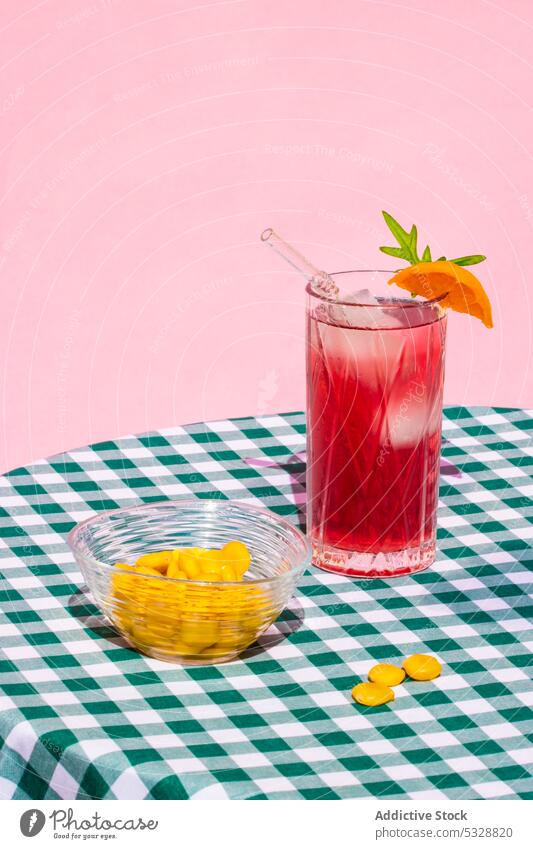 Glass of red cocktail near bowl of lupin beans glass drink beverage orange refreshment table serve ice cold straw delicious checkered citrus fruit alcohol slice