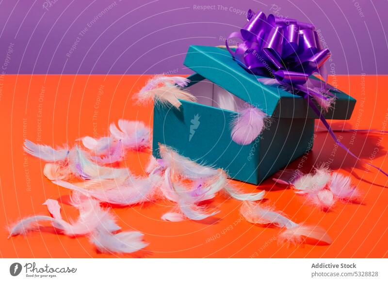 Opened gift box with feathers on table colorful present surprise bow bright vivid celebrate festive carton package design vibrant holiday event birthday purple
