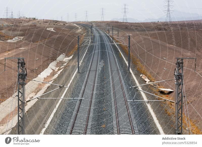 Dual gauge railway tracks with power lines speed motion transport landscape infrastructure passage route terrain railroad train nature grass dry construction