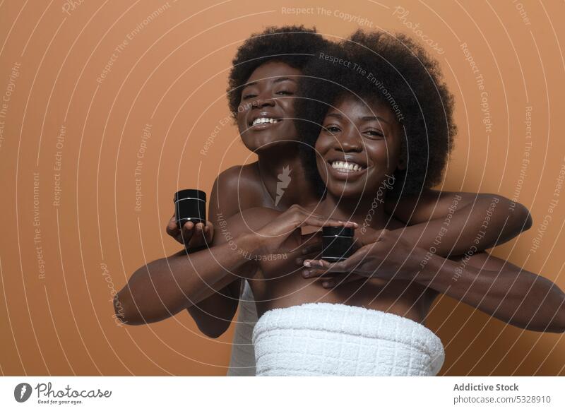 Cheerful black women showing bottles of cosmetic model skin care cream mockup advertise smile afro cheerful female happy curly hair positive moisture
