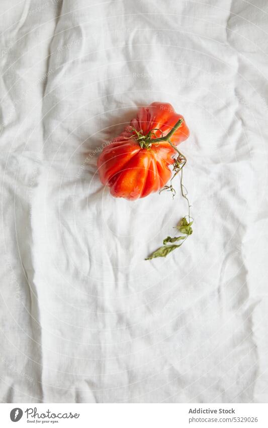 Fresh ripe beef tomato on white clothing red fresh raw leaf branch vegetable fabric stem natural food delicious healthy tasty rough vitamin harvest nutrition