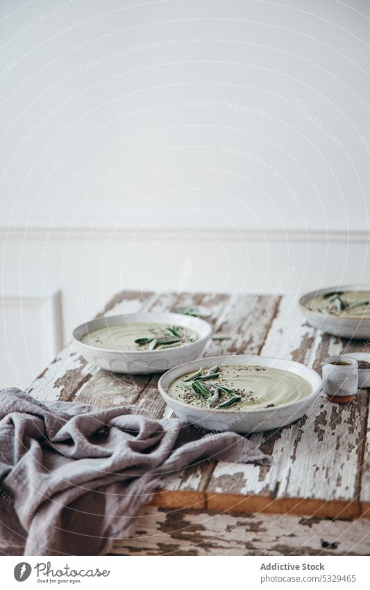 Served table with bowls of cream soup seed healthy food serve sage healthy soup spring soup dish portion gourmet ceramic meal herb green rustic cuisine puree