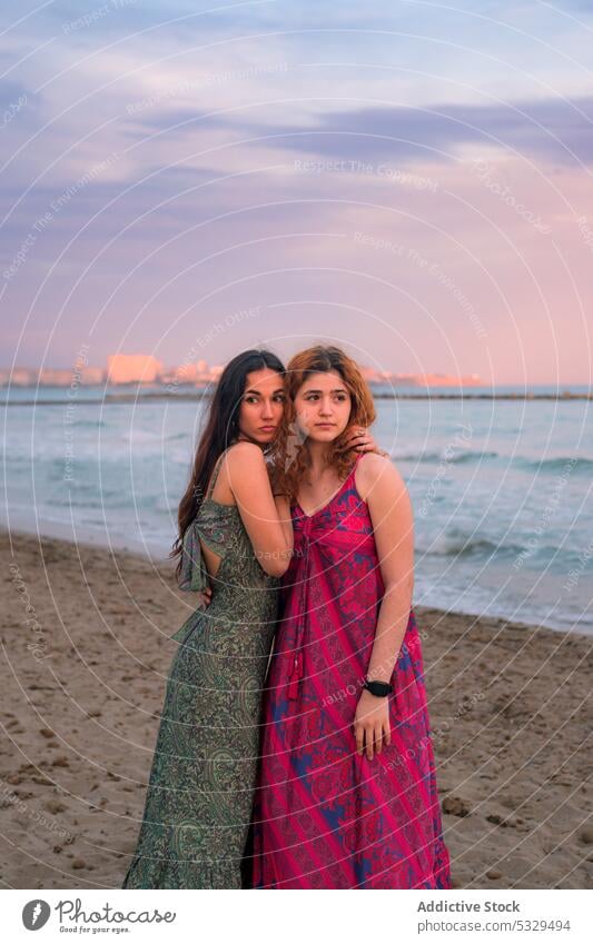 Dreamy women hugging on beach in sunset light friend sea summer evening vacation sand coast female shore friendship ocean pensive sky together thoughtful young