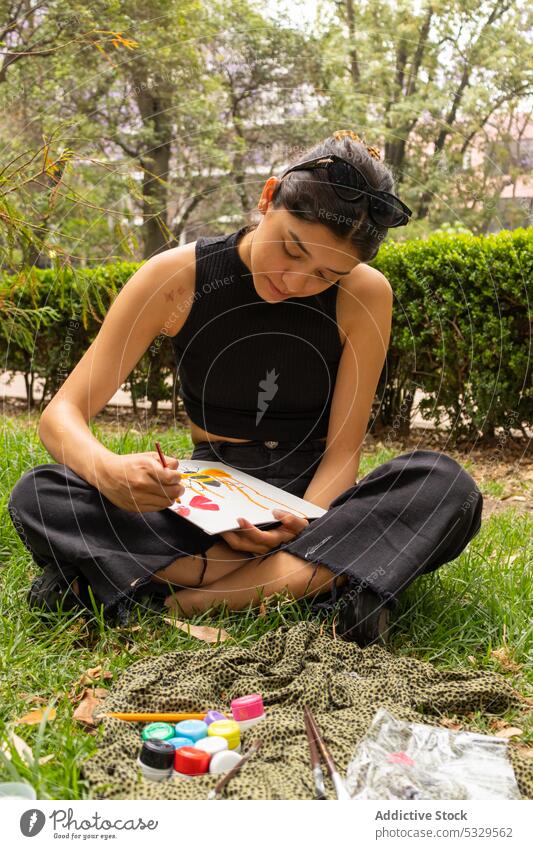 Young woman drawing in nature paint artist painter rest hobby inspiration paintbrush creative paper sit young plant talent casual grass skill female joy craft