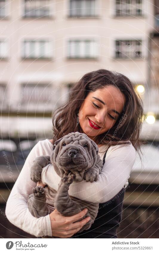 Happy woman hugging cute pet dog on terrace embrace owner evening building companion adorable friend positive female domestic happy canine animal smile city