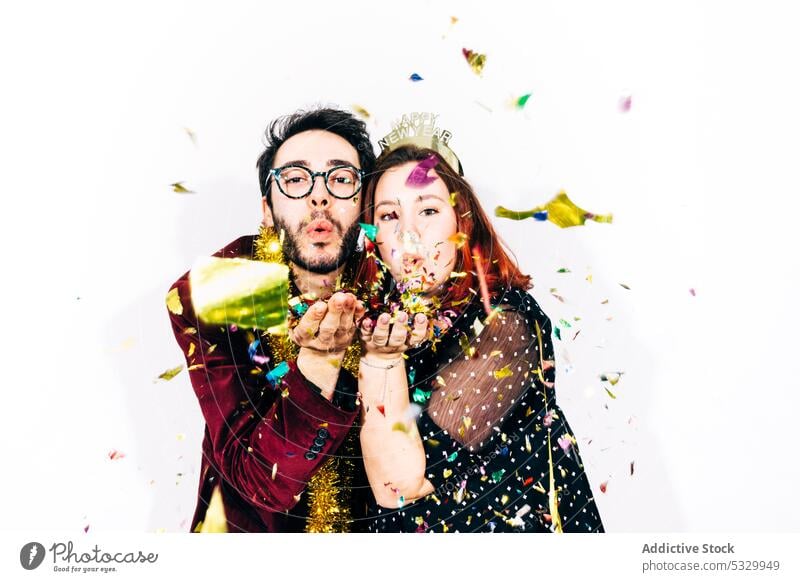 Cheerful friends in stylish wear during New Year party confetti christmas new year blow alcohol enjoy festive portrait celebrate man woman drink having fun