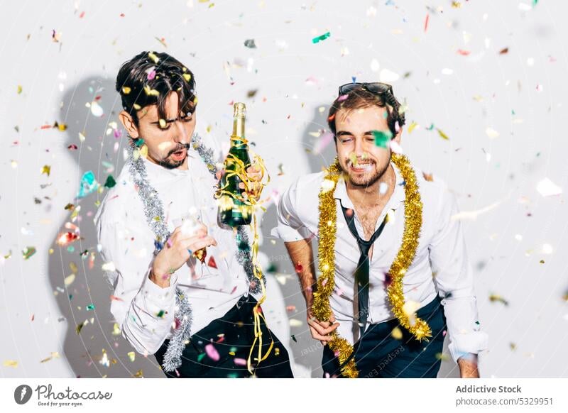 Best friends with bottle of champagne having fun during party best friend christmas new year celebrate alcoholic men portrait tinsel confetti stylish enjoy