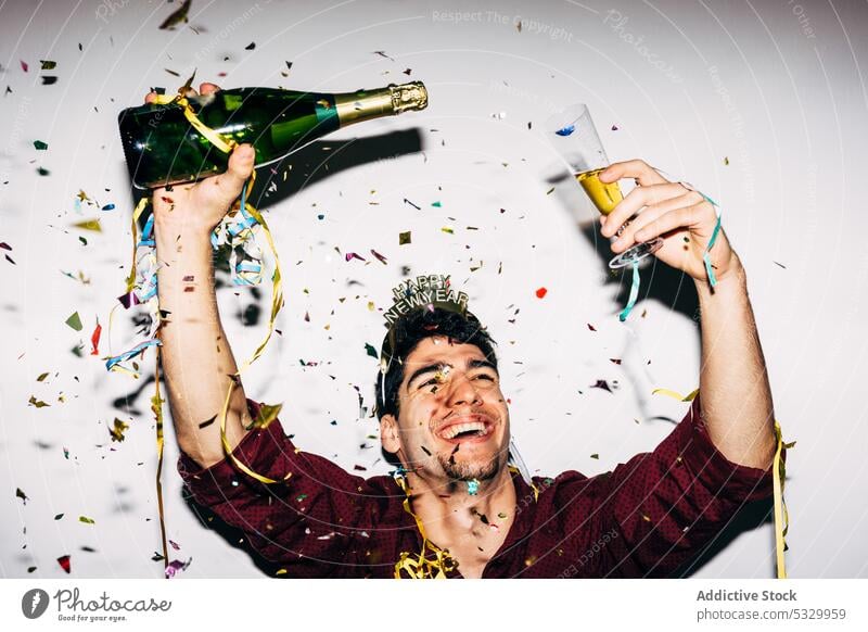 Cheerful man with champagne celebrating New Year holiday new year happy alcohol drink celebrate arms raised party portrait festive bottle confetti alcoholic