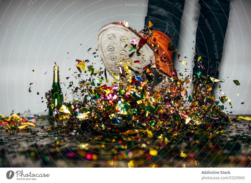 Faceless man in stylish boots kicking pile of confetti during party festive celebrate holiday champagne multicolored style trendy bottle alcoholic drink paper