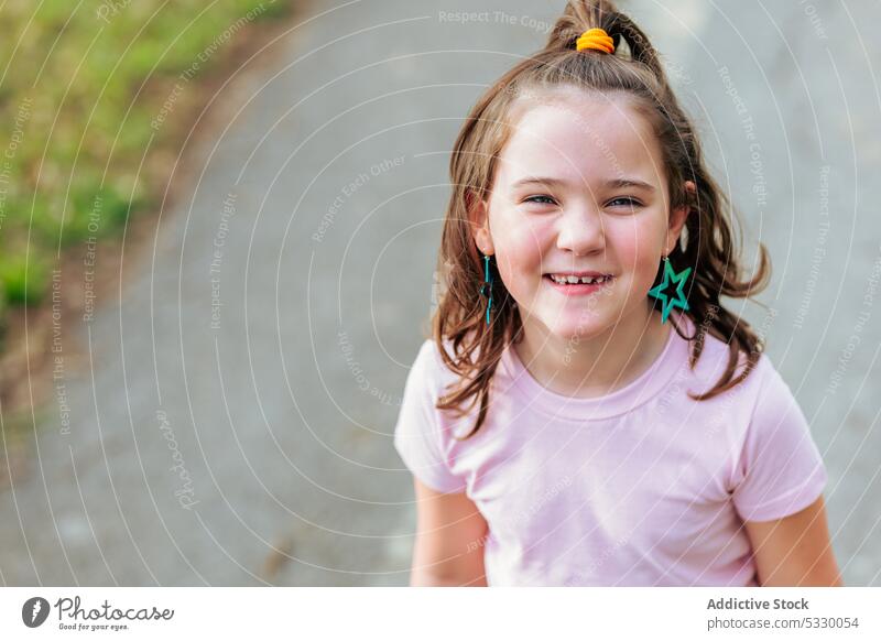 Happy little girl with ponytail hair on road smile portrait cheerful kid child childhood happy asphalt pleasant positive glad sincere charming delight street