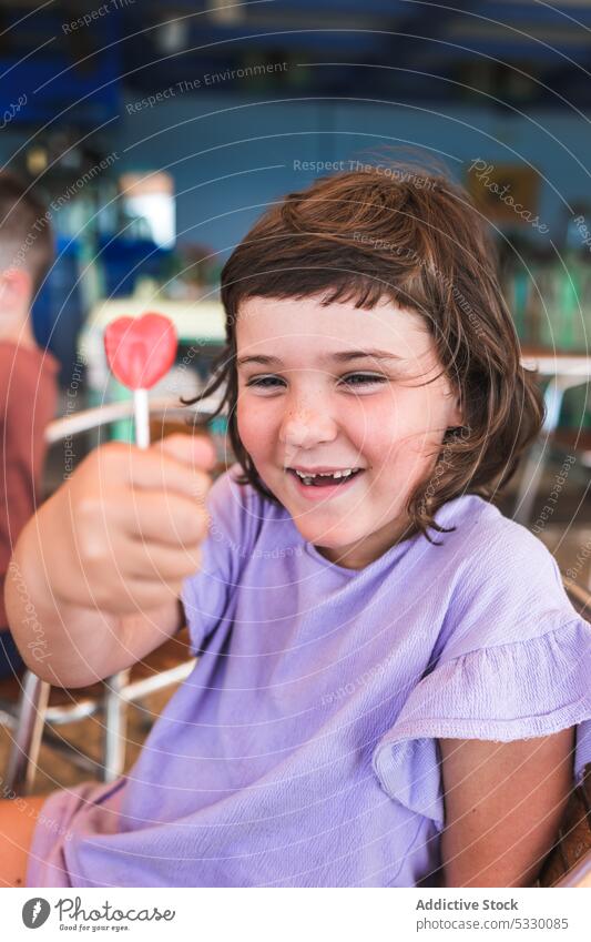 Smiling girl with yummy lollipop in cafe child sweet kid dress smile dessert positive preschool cheerful happy childhood adorable cute candy delicious joy
