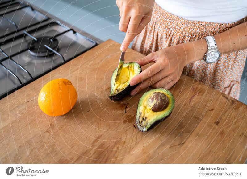 Crop woman peeling avocado while cooking delicious breakfast toast croissant empanada knife cutting board prepare healthy food orange fresh yummy appetizing