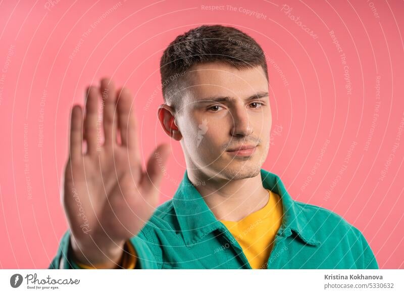 Serious young man showing rejecting gesture by stop finger sign. Dont play me hand no palm warning adult background girl studio denial refusal rejection