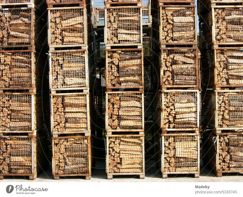 Carefully stacked square containers with firewood in the sunshine on an open area with storage yard in Schloß Holte-Stukenbrock near Gütersloh in East Westphalia-Lippe, Germany