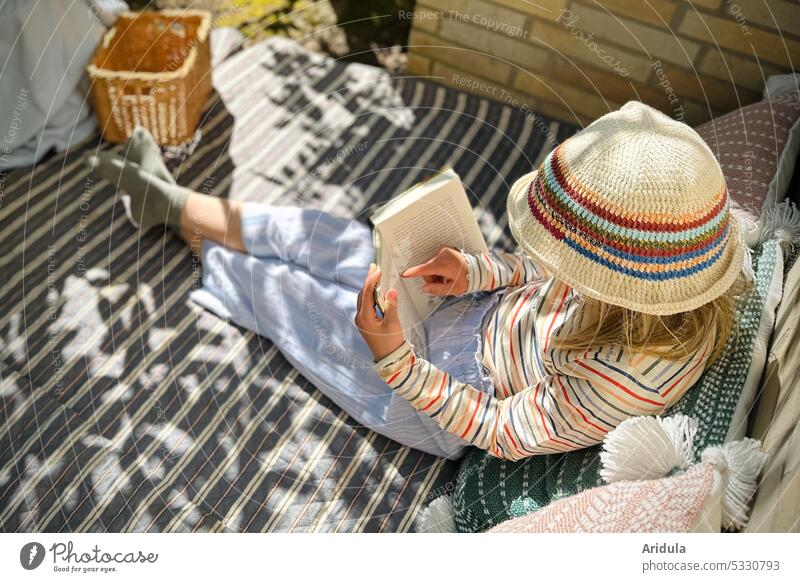 Girl sitting on blanket with pillow and reading a book Book Reading Child Infancy Schoolchild Summer Sun Light Sunlight Study Education Cozy picnic blanket