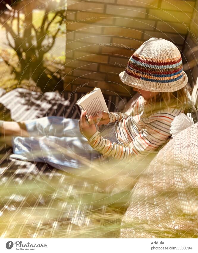 Girl made herself comfortable with a book Book Reading Garden Cozy Corner Knitted hat Cap Sunlight Light Shadow Reflection blurriness Exterior shot Evening