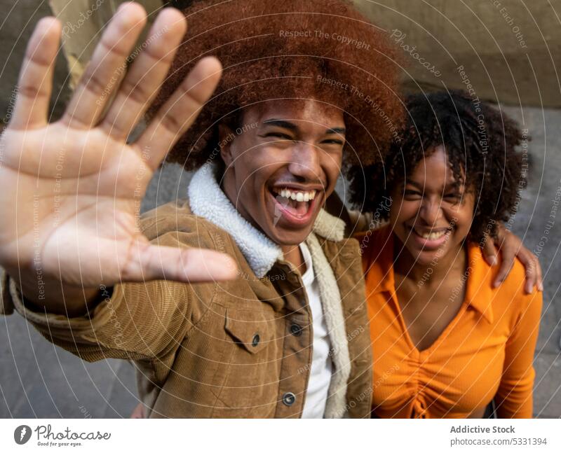 Smiling black couple standing in embrace and laughing at camera hello cheerful greeting gesture happy portrait smile friendly african american ethnic positive
