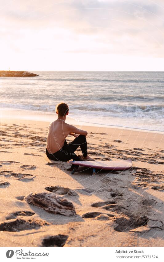 Anonymous surfer with surfboard resting near sea man beach sunset vacation relax summer seascape male enjoy picturesque sand shirtless coast ocean shore evening