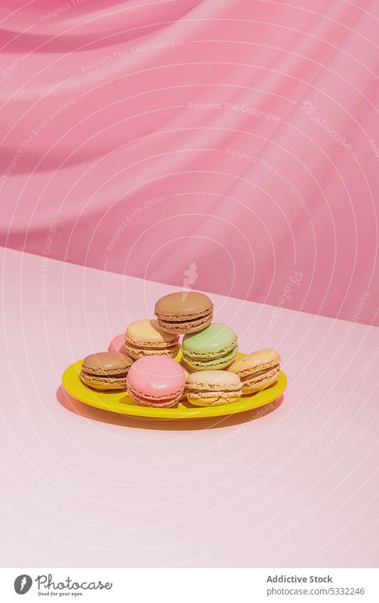 Colorful macaroons on round plate against pink background dessert sweet delicious yummy tasty food colorful confectionery sugar calorie pastry multicolored