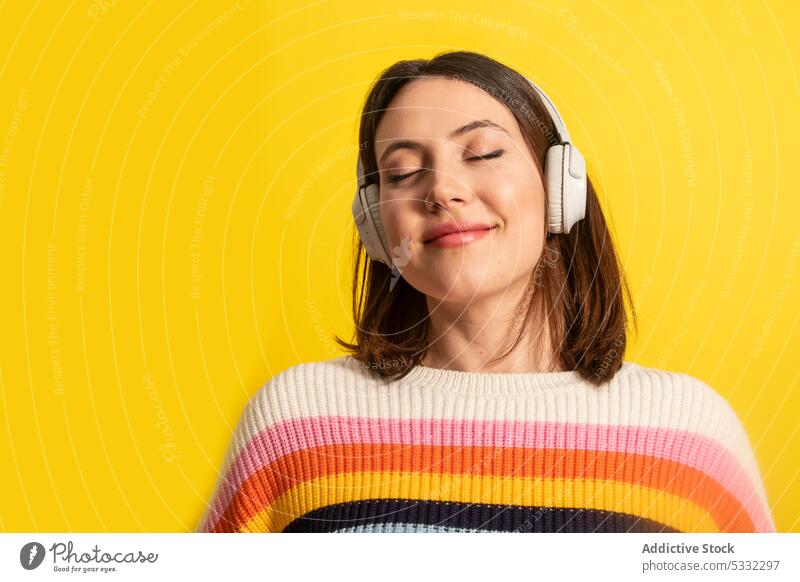 Smiling woman in headphones listening to music meloman happy positive song enjoy melody eyes closed wireless casual bright style young female device modern