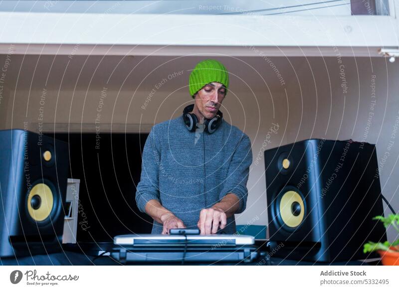 Man playing on DJ mixing console at home man dj music mixer sound equipment beanie audio controller button entertain record switch contemporary electronic
