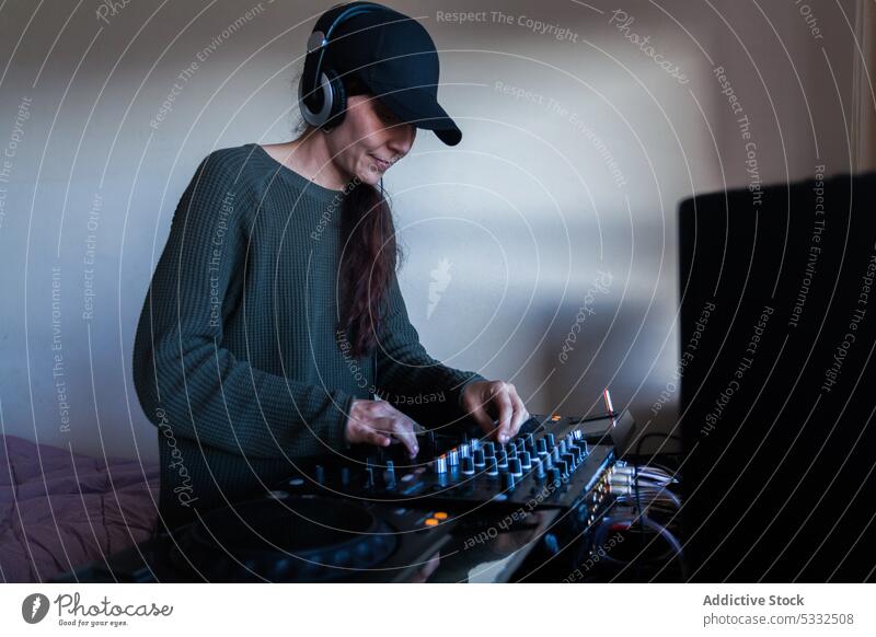 Female DJ using mixing console at home woman smile happy dj listen music studio controller device button adult professional audio female headphones entertain