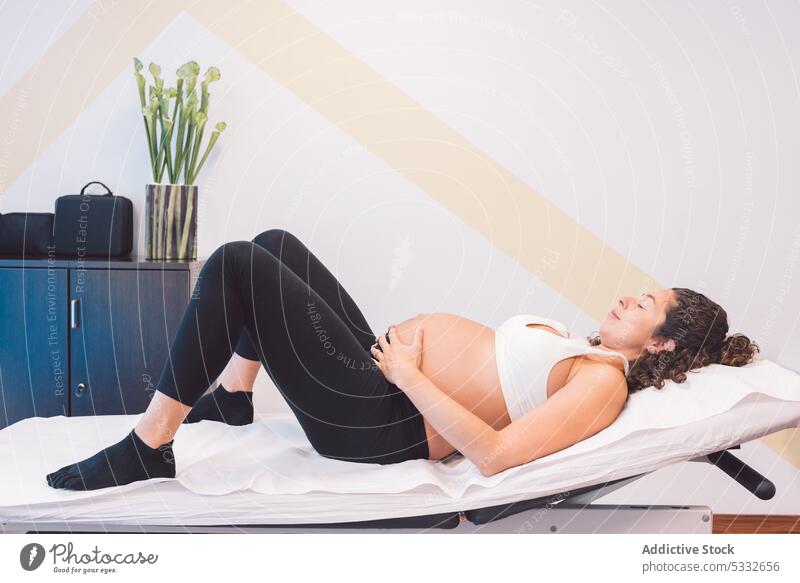Pregnant patient lying on massage table in clinic woman pregnant relax osteopathy rest bed expect pregnancy belly tummy female chill comfort wellness touch