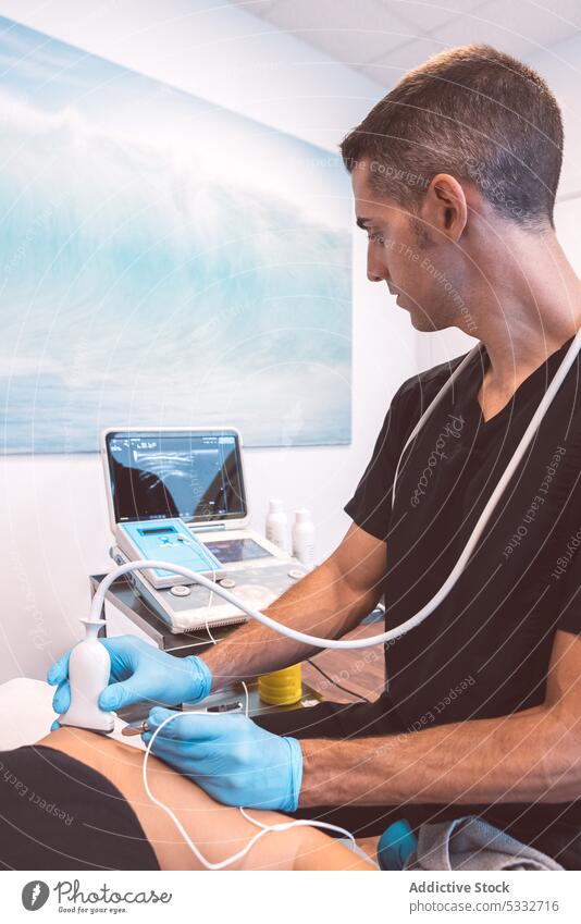 Concentrated doctor doing ultrasound scan of patient man examine clinic modern appointment equipment treat physiotherapy medicine health care hospital