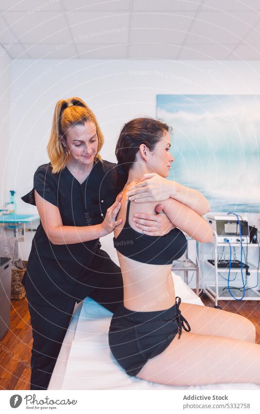 Focused osteopath massaging back of client in clinic women massage patient therapist masseur rehabilitation treat procedure specialist session doctor recovery